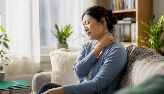 Woman massaging stiff neck at home desk