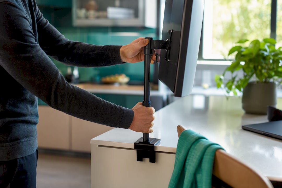 Hands adjusting monitor height on desk