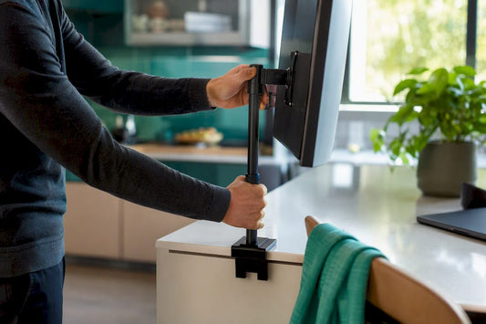 Hands adjusting monitor height on desk
