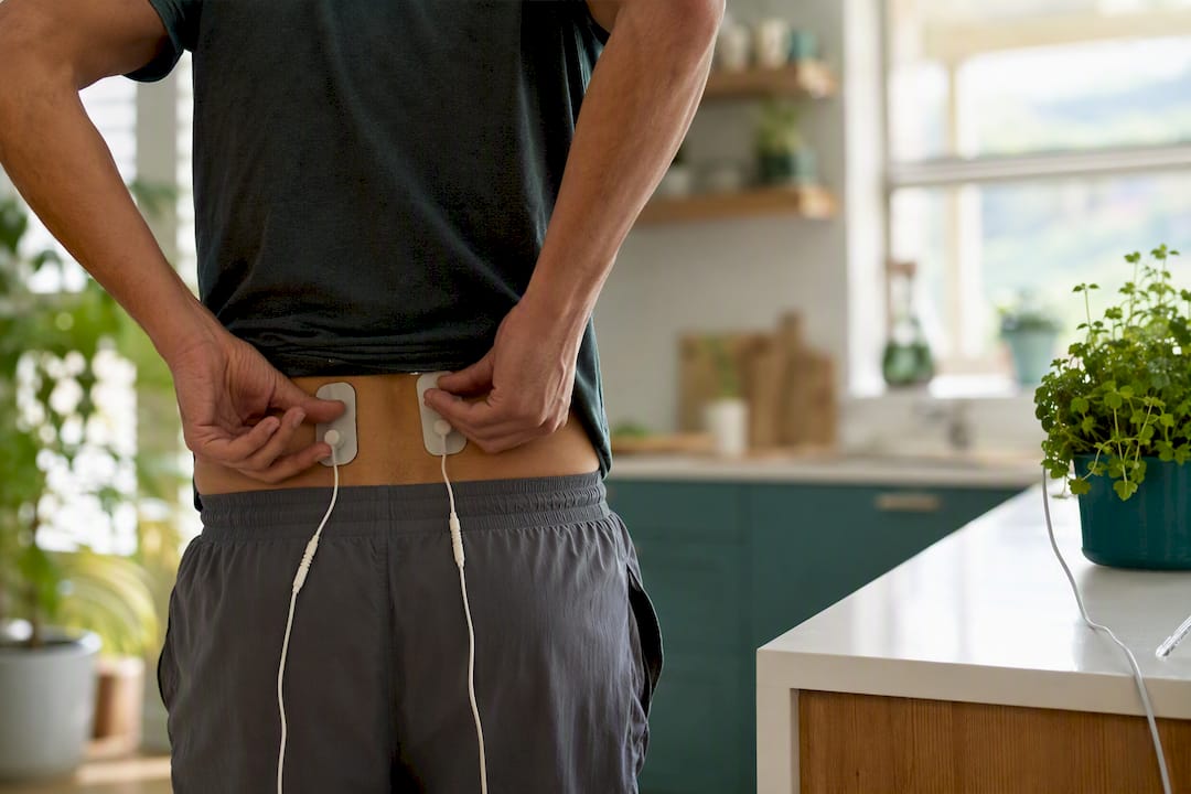 Hands applying EMS electrodes on lower back