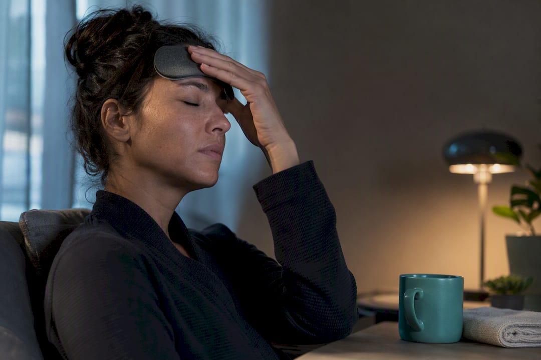 Person applying a cooling migraine mask
